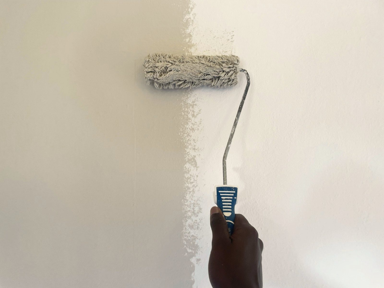 Een wand wordt met een roller wit geschilderd