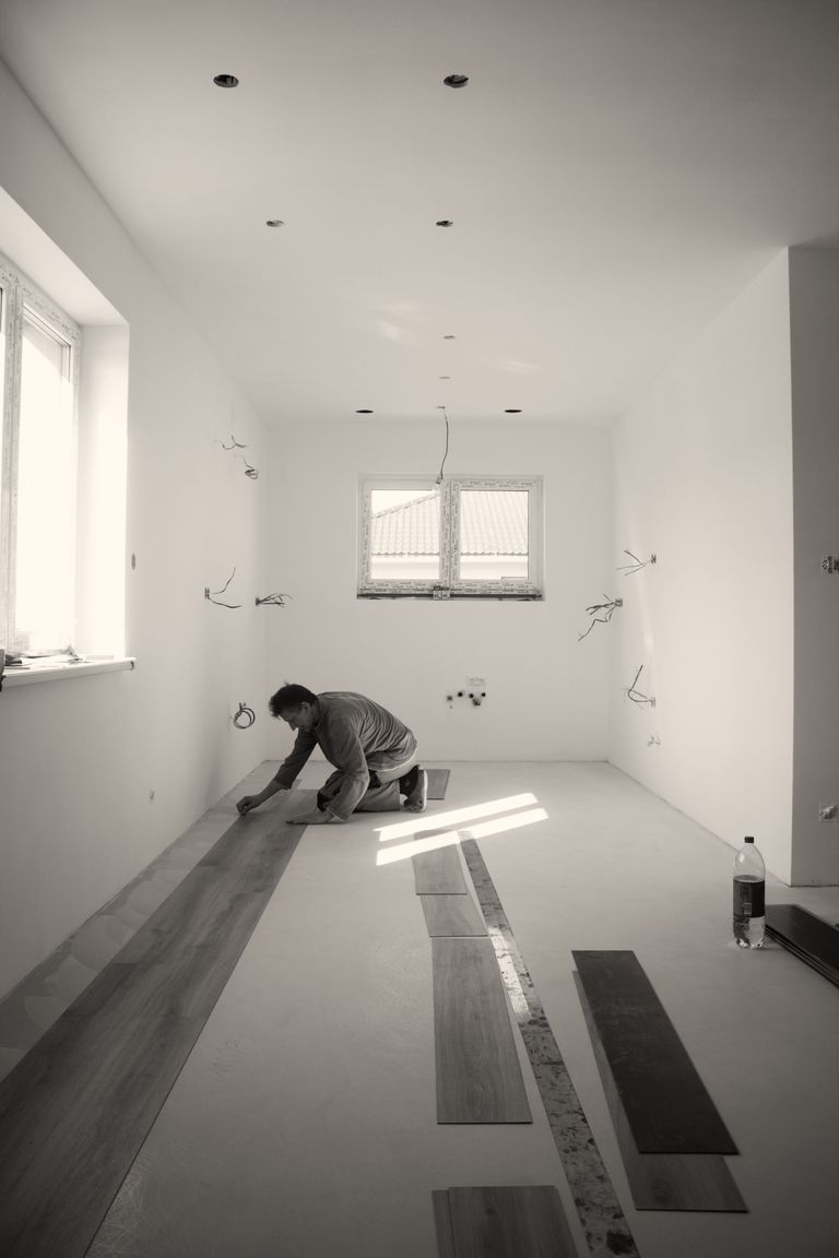 Vakman legt een nieuwe vloer in een lege kamer