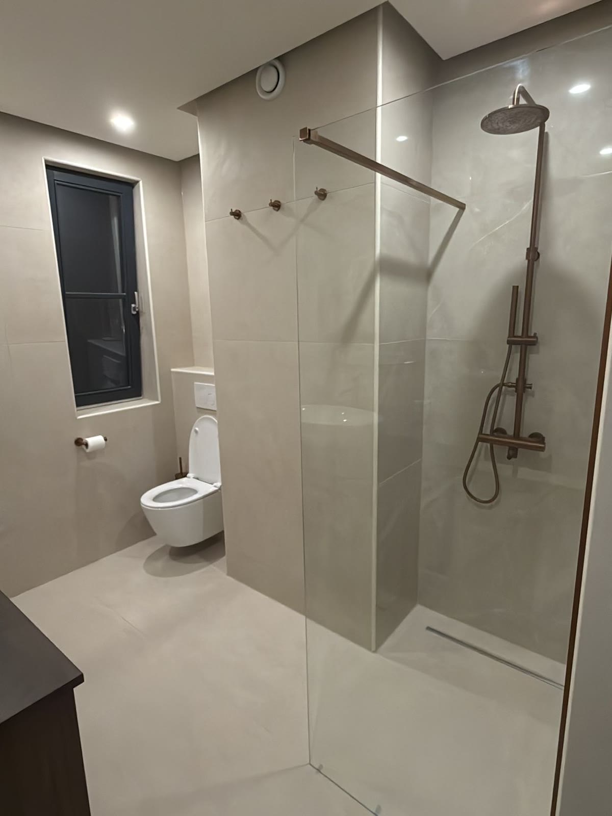 Na: Dezelfde badkamer met inloopdouche, glazen wand en hangtoilet