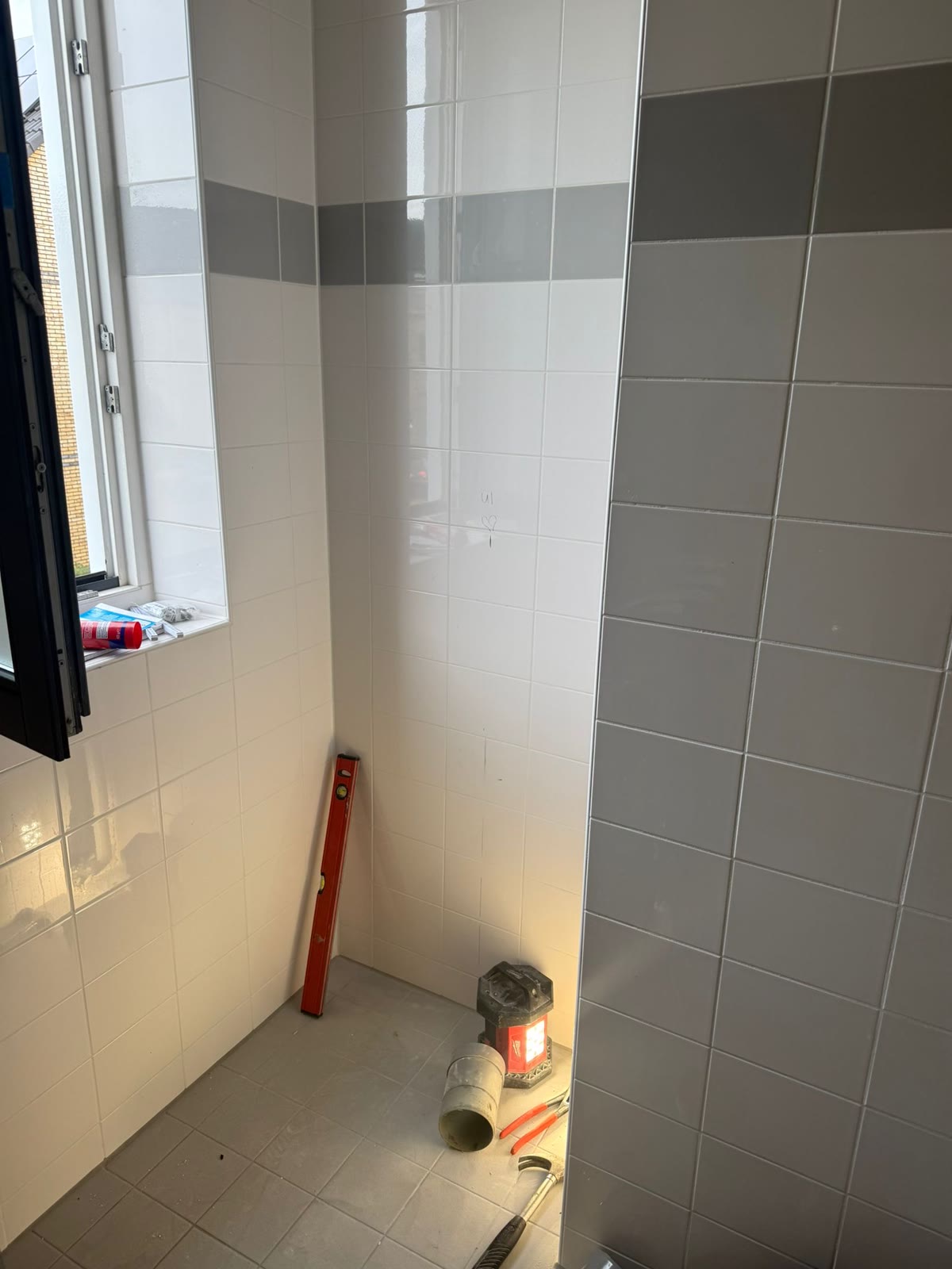 Voor: Badkamer voor de verbouwing, met wit tegelwerk en een grijze band op ooghoogte