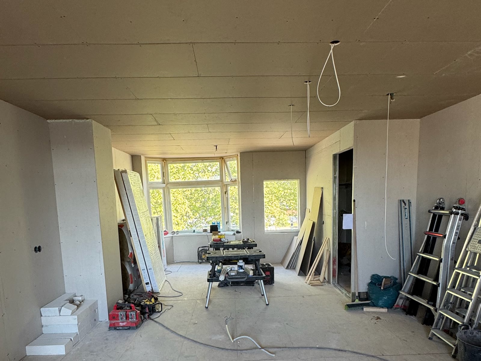 Dezelfde woonkamer dichtgezet met gipsplaat, wanden en plafond gesloten, het leidingwerk weggewerkt