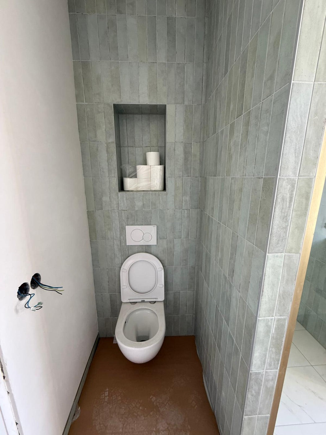 Toilet met sage-groene tegels en verlichte nis, opgeleverd door Woonklasse